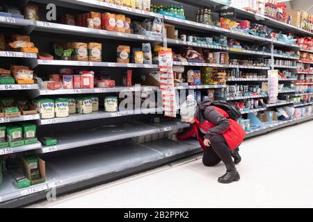 London, UK. 3rd Mar, 2020. A shopper looks for baking flour on the almost-empty shelves at a supermarket in London, Britain, on March 3, 2020. British Prime Minister Boris Johnson on Tuesday set out the government's action plan to tackle the spread of the novel coronavirus, as the number of infections reached 51 across the country. Credit: Xinhua/Alamy Live News Stock Photo
