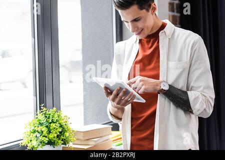 handsome student in shirt using digital tablet in apartment Stock Photo