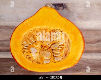 Cut half of orange hokkaido pumpkin on wood free space flat lay. Top view on rustic wooden table with cutaway fresh squash. Seasonal, dieting, vegetar Stock Photo