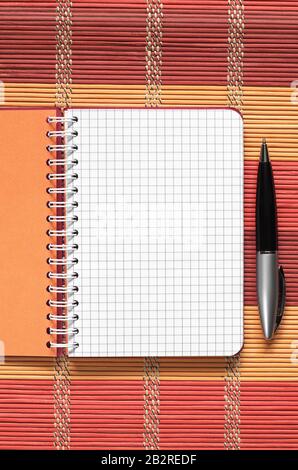 Opened notebook with pen on a colorful bamboo napkin, top view Stock Photo
