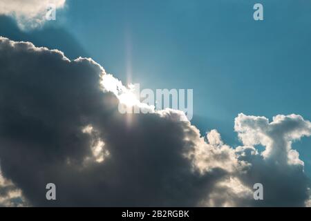 dark clouds covering the sun and blue sky. fast weather change Stock Photo