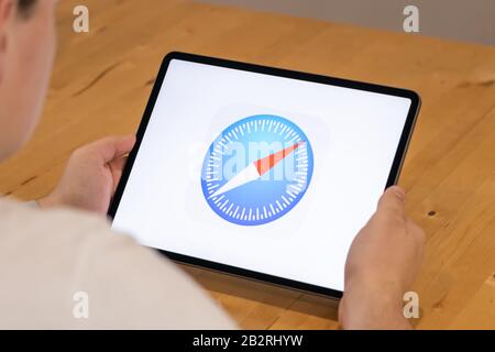 Man sitting a desk using an iPad Pro with the Safari browser icon on screen. Stock Photo