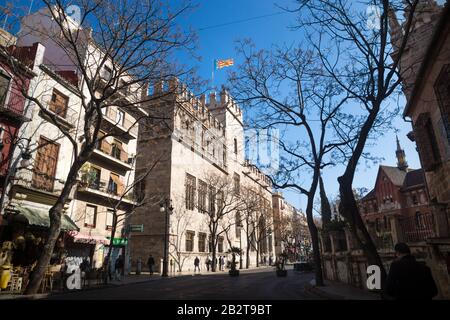 Valencia, Spain - 17 February 2020: Street view with Fassade of Lonja de la Seda with pedestrians behind spring blossom trees Stock Photo