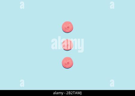Three spots of pink paint on a blue background. Cream, cosmetic, topping for your design. Stock Photo