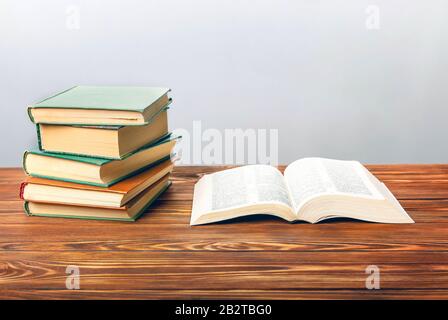 Open book on the table with other books on a gray background. Stock Photo
