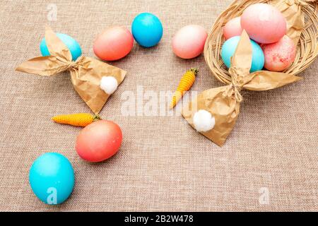 Easter bunny (rabbit) paper gift wrapping with knitted carrots idea. Eggs in wicker basket. Handicraft (homemade) concept for children (kids). On clot Stock Photo