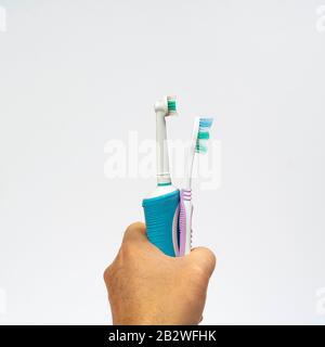 an electric toothbrush and a traditional one in hand Stock Photo