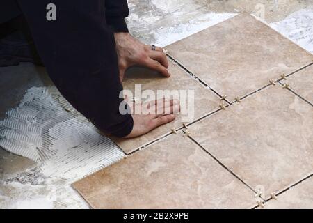 Ceramic tiles are being put down by a contractor on a cement floor Stock Photo
