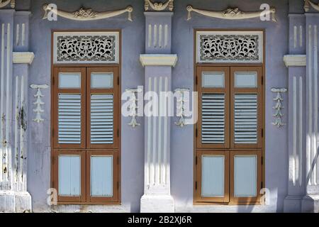 Singapore shophouse with white and brown wooden shutters, grey exterior and decorative carvings in historic Little India in front view Stock Photo