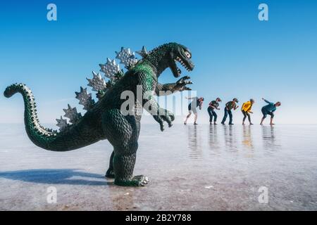 Tourists running from scary dinosaur forced perspective, Uyuni Salt Flats aka Salar de Uyuni in Bolivia, South America. Stock Photo