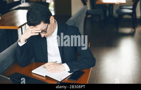 Thinking caucasian businessman is trying to write something while waiting a phone call Stock Photo