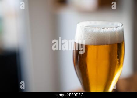Detailed shot of glass filled with freshly poured foamy golden beer Stock Photo