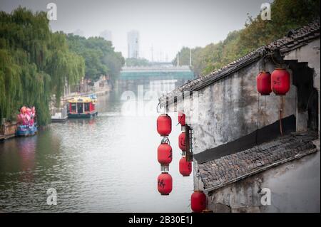 Wuxi, China - October 2019: Ancient town, Wuxi, Jiangsu Province. Chinese lanterns hang from an ancient building along the Grand Canal - China Stock Photo