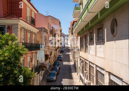 Alleyway in city with various parked cars between various commercial and residential buildings Stock Photo