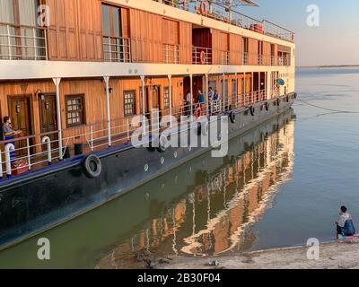 Mingun, Myanmar - January 2020: River cruise ship on the banks of the Irrawaddy River at sunset Stock Photo