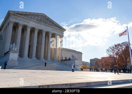 United States Supreme Court on sunny day in D.C. with the USA flag waving in the sunlight.