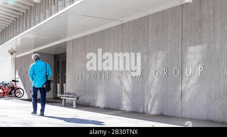 Man walks by a sign for The World Bank Group at their global headquarters in Washington, D.C. Stock Photo
