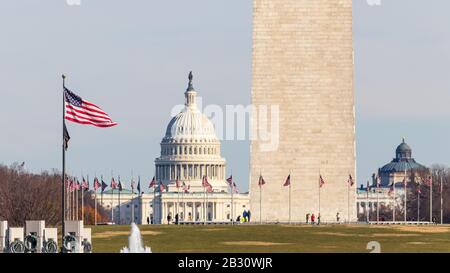 American flag waving while looking down the National Mall at the base of the Washington Monument and the US Capitol Building. Stock Photo