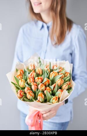 Orange color tulips in woman hand. Young beautiful woman holding a spring bouquet. Bunch of fresh cut spring flowers in female hands Stock Photo