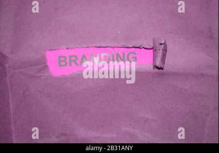 The word Branding written under torn paper with silver letters on pink background Stock Photo
