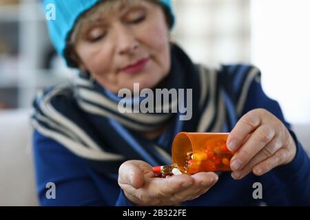 Elderly woman puts capsules from can in palm Stock Photo