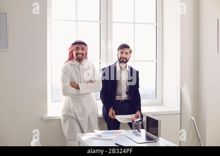 Arab and European business people are standing together in a modern office. Stock Photo