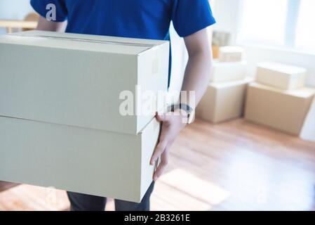 Asian young delivery man holding and carrying two cardbox standing in workplace. Stock Photo