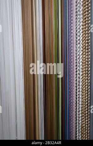 Textile strings and ropes hangs in a fabric shop. Abstract background ...