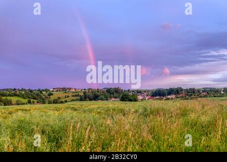 Rainbow over the summer field and road after the evening storm, sunset in countryside with beautiful sky Stock Photo