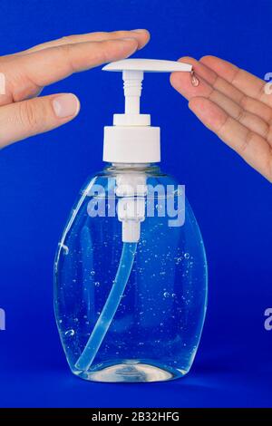 A close up of a person applying hand sanitizer on a dark blue background Stock Photo