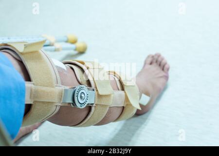 Asian senior or elderly old woman patient with bandage compression knee brace support injury on the bed in nursing hospital.Orthopedist secures leg br Stock Photo