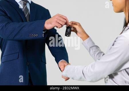 Businessman and businesswoman shaking hands in agreement holding car keys Stock Photo
