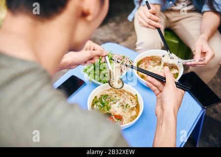 Close up of couple eating pho soup in the city Stock Photo