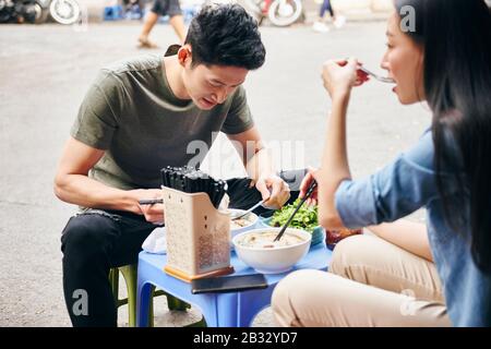 Young couple trying to vietnamese food in the city street Stock Photo