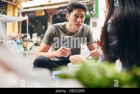 Young couple eating vietnamese food in the city street Stock Photo