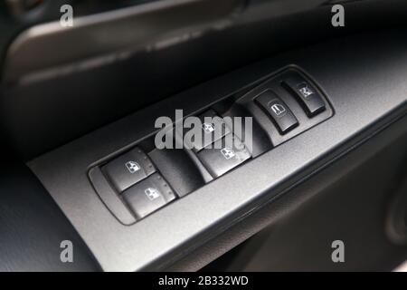 The control buttons for opening and closing windows of doors and electric controls on the door in gray with upholstery in a luxury modern car. Stock Photo