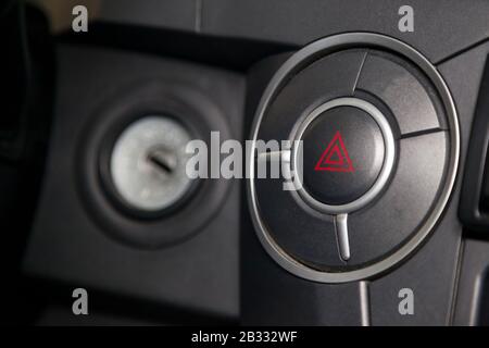 Close-up on emergency round button with red triangle icon on the car plastic dashboard. Problem, crash and damage concept. Stock Photo