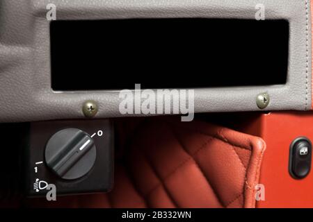 Black button switch for turning electric headlight range adjustment of the car dashboard Stock Photo