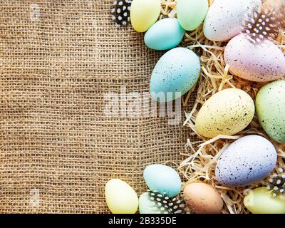 Easter eggs on a sackcloth and straw . Happy Easter  multicolored  easter eggs. Background with easter eggs. Flat lay, top view. Stock Photo