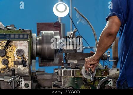 Professional machinist hand working with lathes machine in metalworking factory, lathe metalworking industry concept Stock Photo