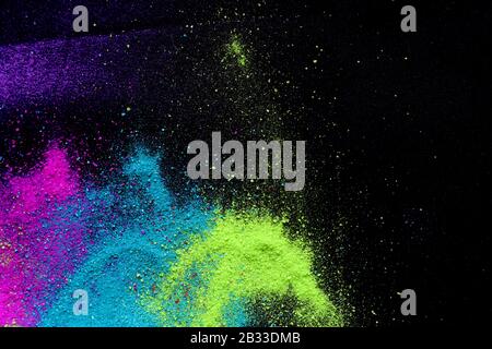 Multi-colored powder sprayed on black background. Holi celebration Stock Photo