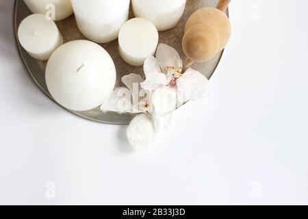 Still Life Composition with White Candles and Dry Orchid Flowers on a Tray on a White Background with Copy Space. Stock Photo