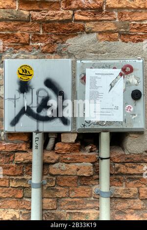 Graffiti on street walls, Venice, Italy. Immigrants welcome sticker and hammer and sickle Stock Photo