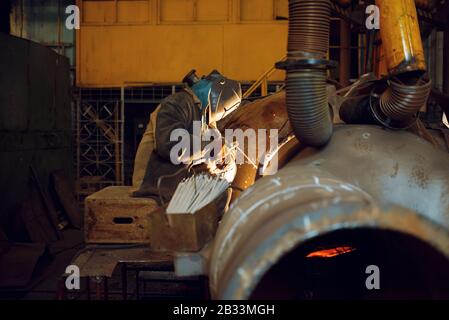 Welder works with metal on factory, welding skill Stock Photo