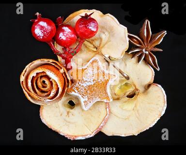 Christmas homemade decoration objects  made  of dry red orange peels, cones, berries  and apples. Isolated on black night macro Stock Photo