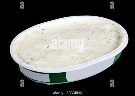 Oval open plastic box with soft cheese with garlic and dill. Isolated on black  macro studio shot Stock Photo