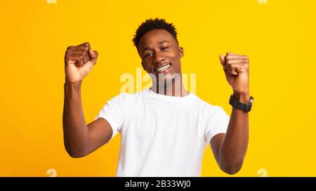 Young cheerful african guy moving dancing on yellow Stock Photo