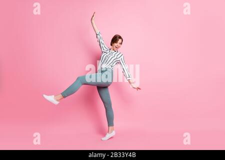 Full size photo of positive content youngster girl have fun spring weekends raise hands laugh feel rejoice wear stylish clothing isolated over pink Stock Photo