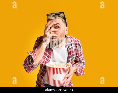 Shocked guy closes eyes his hand, holding bucket Stock Photo