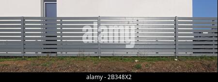 The rural long fence is made of horizontal wooden boards and painted with gray oil paint. Sunny winter day panoramic landscape Stock Photo